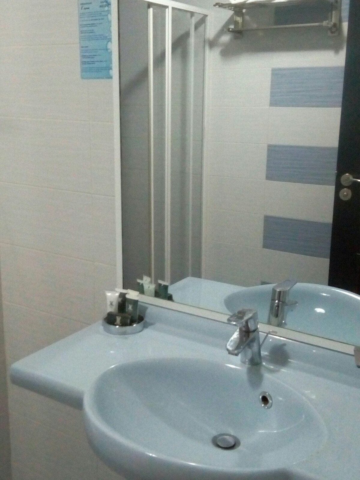 A bathroom with a white sink, a mirror, and a shower enclosure.