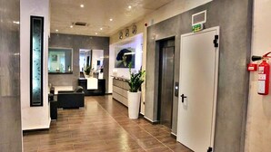A modern hotel lobby with a reception desk, a large potted plant, a fire extinguisher, and an elevator. - ABC Hotel - Alger Centre (Algiers)