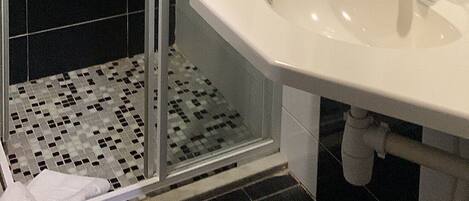 Un baño moderno con ducha de vidrio, un lavabo blanco y un espejo grande.
