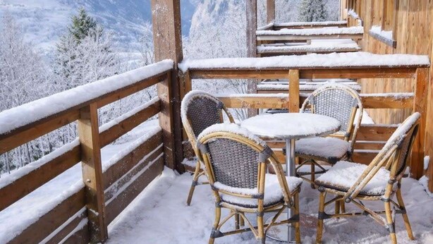 A wooden balcony with a view of snow-covered mountains, wicker chairs, and a table. - Beautiful, spacious apt near Arc 1600 (Bourg-Saint-Maurice)
