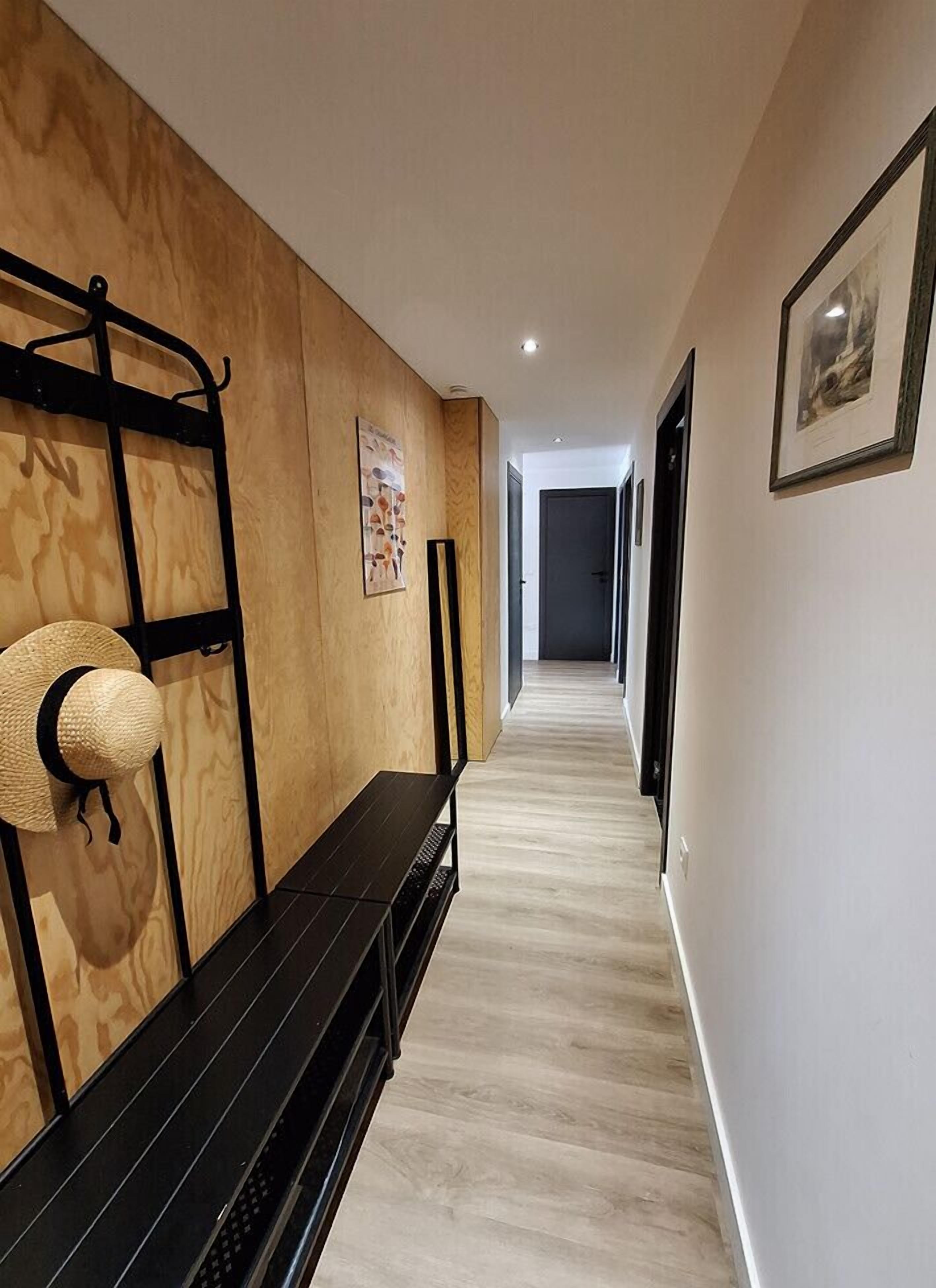Un couloir aux murs recouverts de lambris en bois, avec un banc et des œuvres d’art encadrées.
