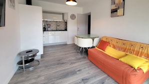 A compact living space with a kitchenette, a dining area, and a sofa with cushions. - Charming love nest near the sea (Fréjus)