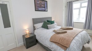A neatly arranged bedroom with a bed, bedside table, and a framed picture on the wall. - Luna Cottage (Holmfirth)