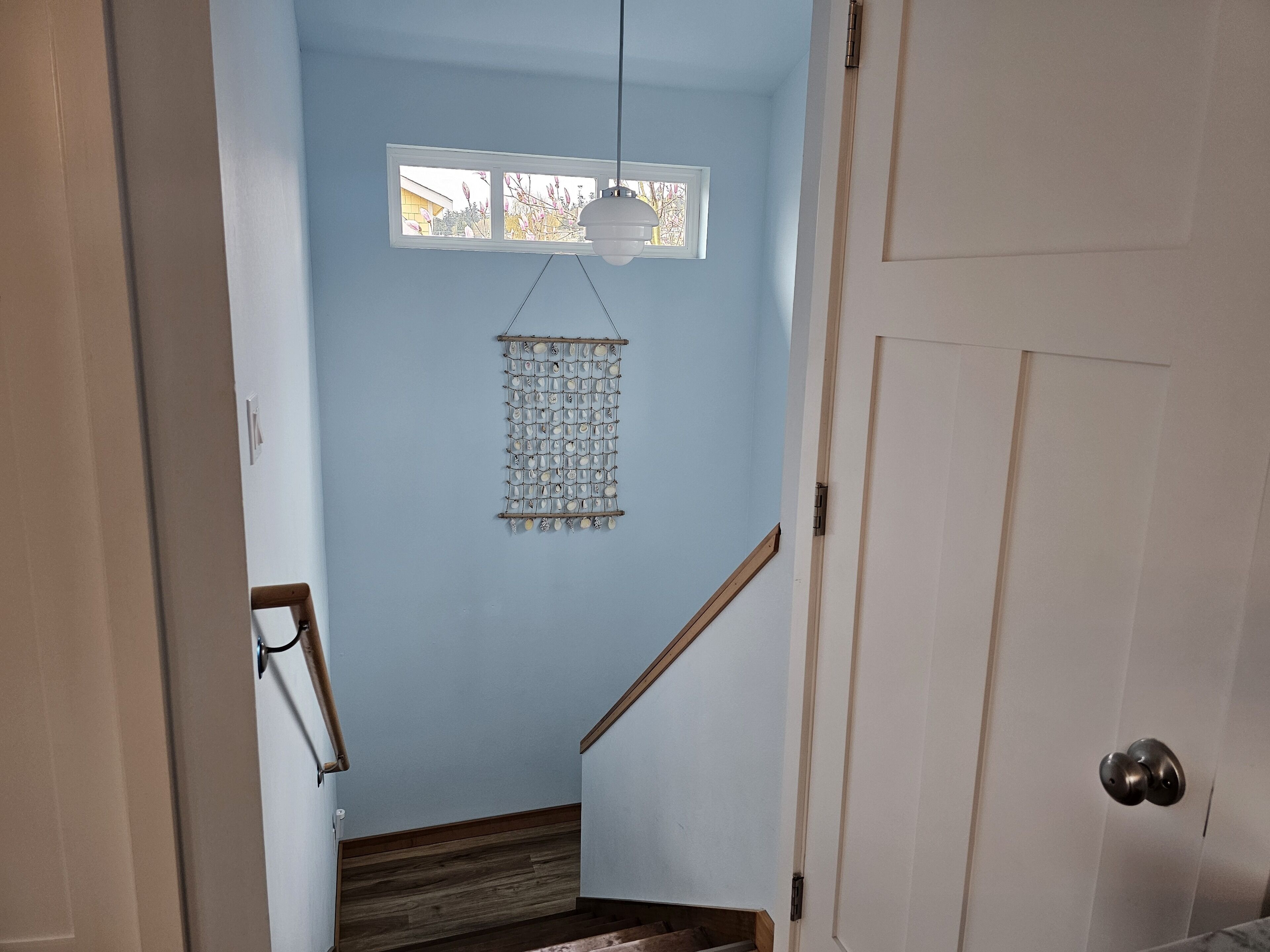 Una escalera con barandilla de madera que lleva a un rellano con un adorno colgante.