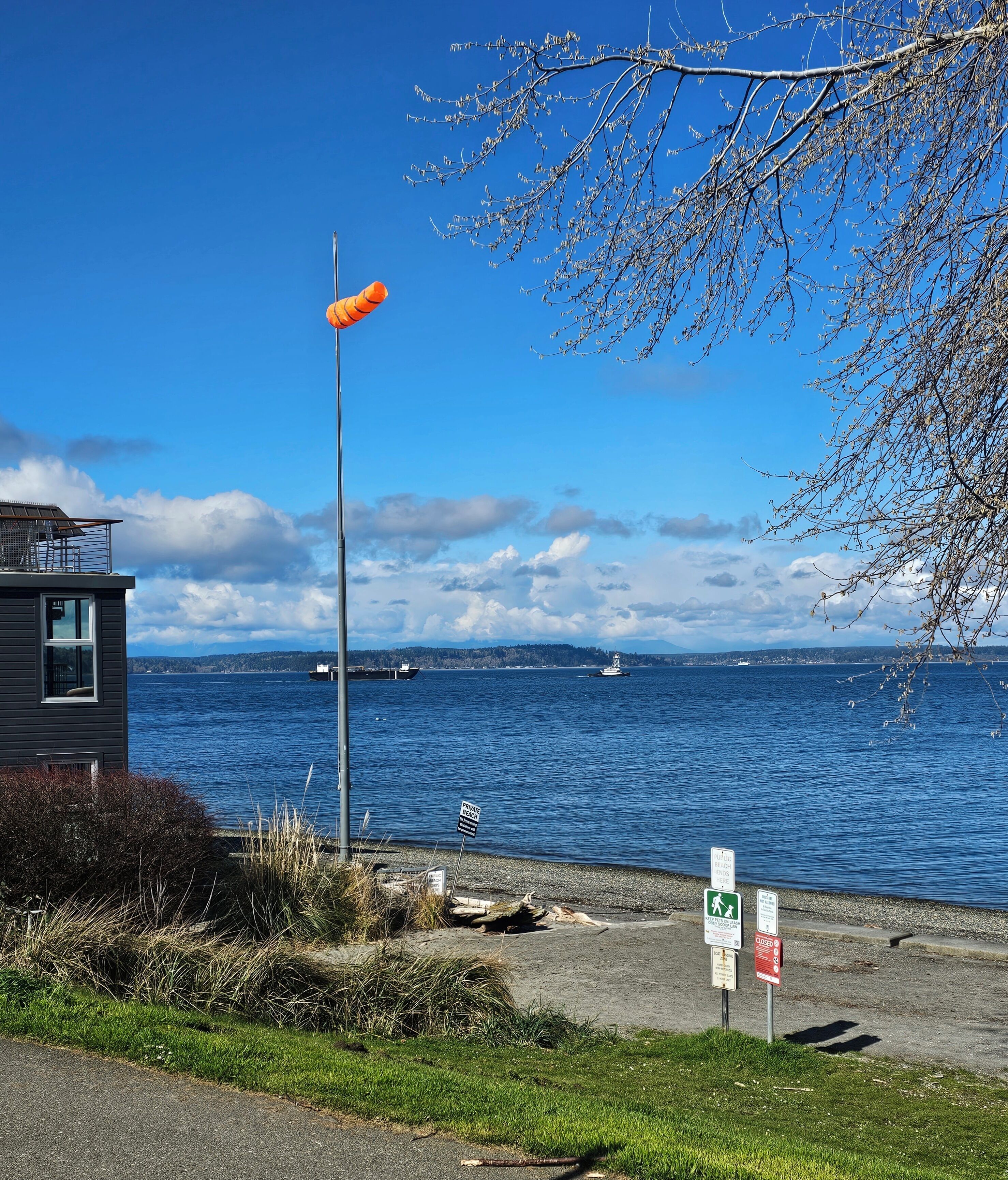 Blick auf die Küste mit einem Gebäude, einem Schild, der einen privaten Strand kennzeichnet, und einem Fußweg.