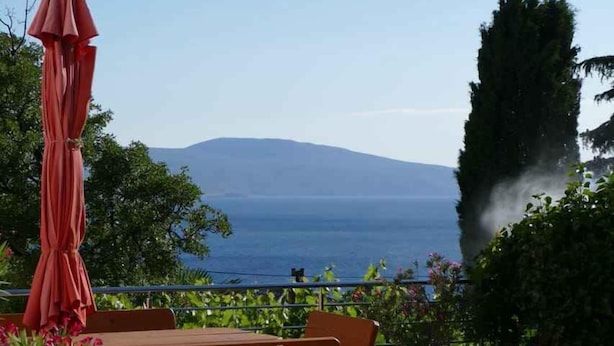A terrace with a view of the sea, a red umbrella, and a wooden bench. - Holiday apartment with Wi-Fi (Novi Vinodolski)