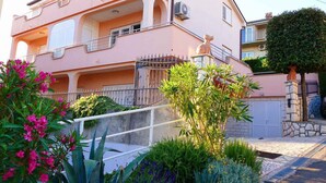 A two-story building with balconies, a gated entrance, and a well-maintained garden with various plants and flowers. - Holiday apartment with Wi-Fi (Novi Vinodolski)