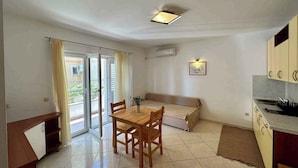 A compact living space with a dining area, kitchenette, and a sliding glass door leading to a balcony. - Holiday apartment with Wi-Fi (Novi Vinodolski)
