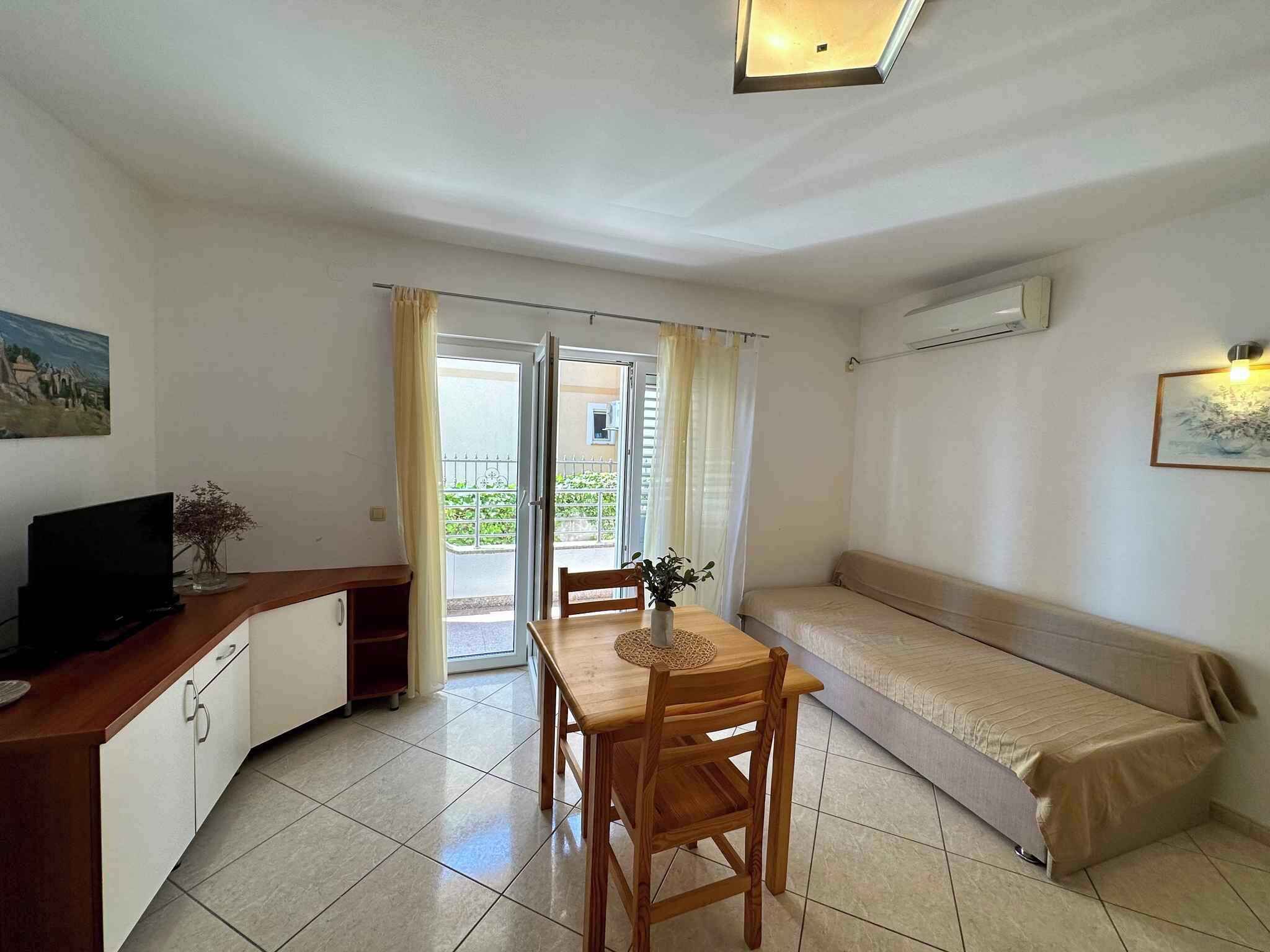 A compact living space with a kitchenette, a dining table with chairs, a sofa, and a sliding glass door leading to an outdoor area.