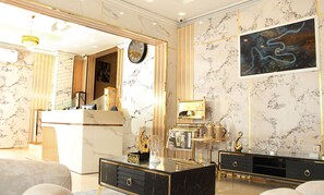 A luxurious room with a marble reception desk, a large mirror, and a modern art piece on the wall. - ALBARAKAH HOTEL (Sharjah)