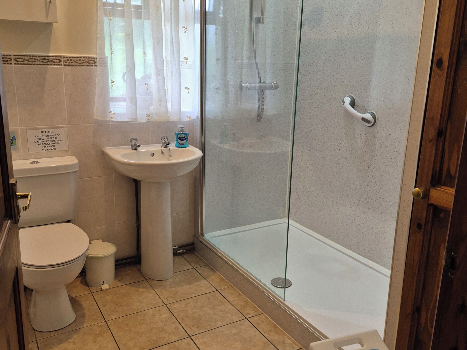 A bathroom with a toilet, sink, and glass-enclosed shower.