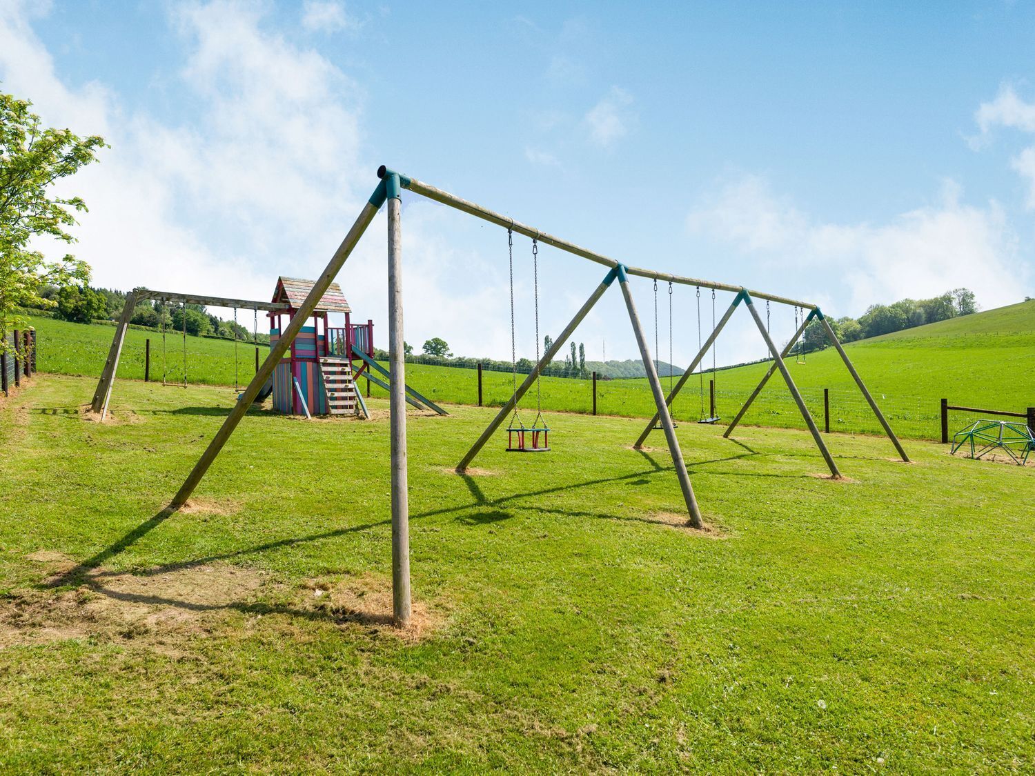 A playground with swings and a small playhouse.