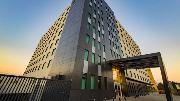 Een modern hoog gebouw met een opvallende ingang en een hekpoort.