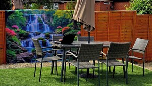 Eine Terrasse mit Esstisch, Stühlen und Sonnenschirm.