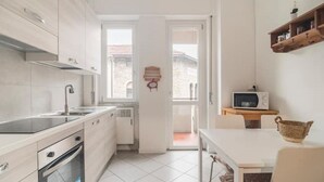 Uma cozinha moderna com armários brancos, forno embutido e micro-ondas sobre uma bancada de madeira.