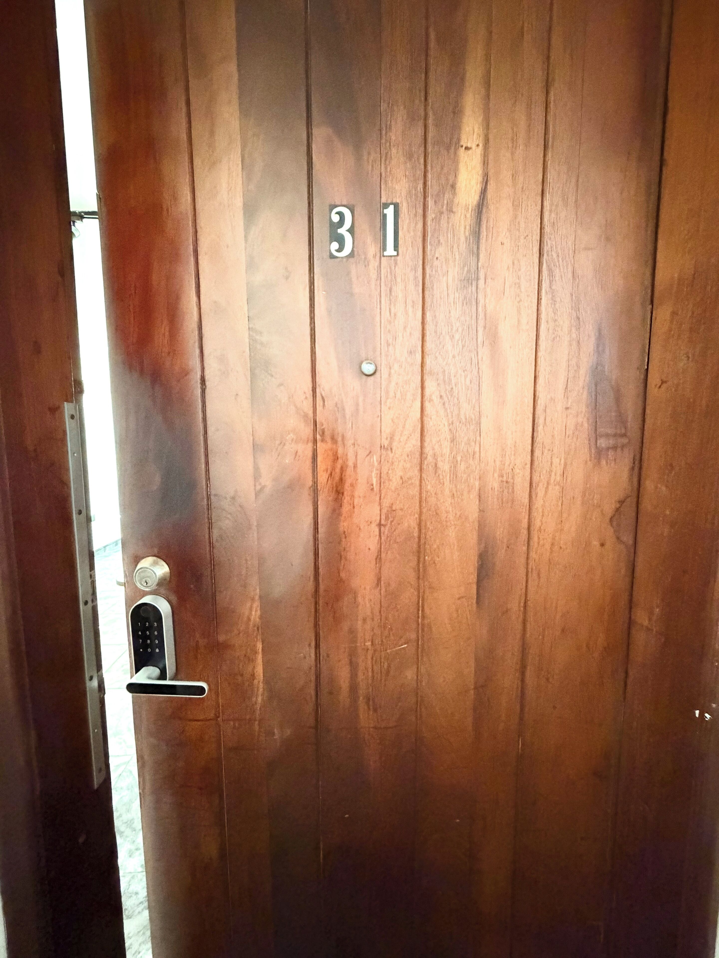Une porte en bois portant le numéro 31, avec un trou de serrure et une poignée de porte.
