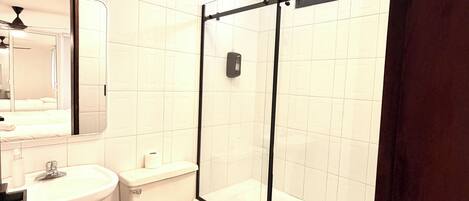 Un baño con inodoro, lavamanos y zona de ducha.