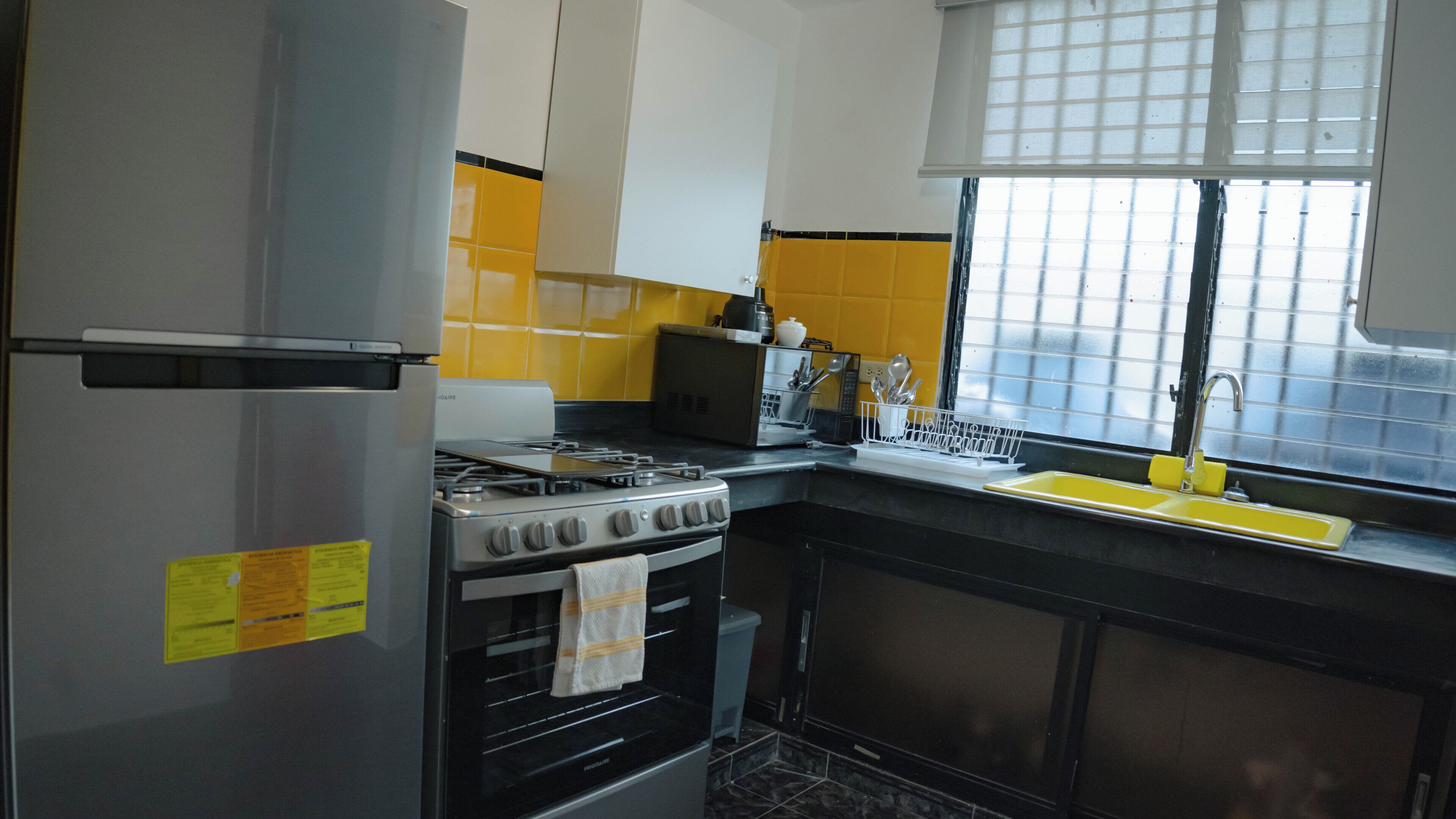 A kitchen with a refrigerator, stove, oven, and sink.