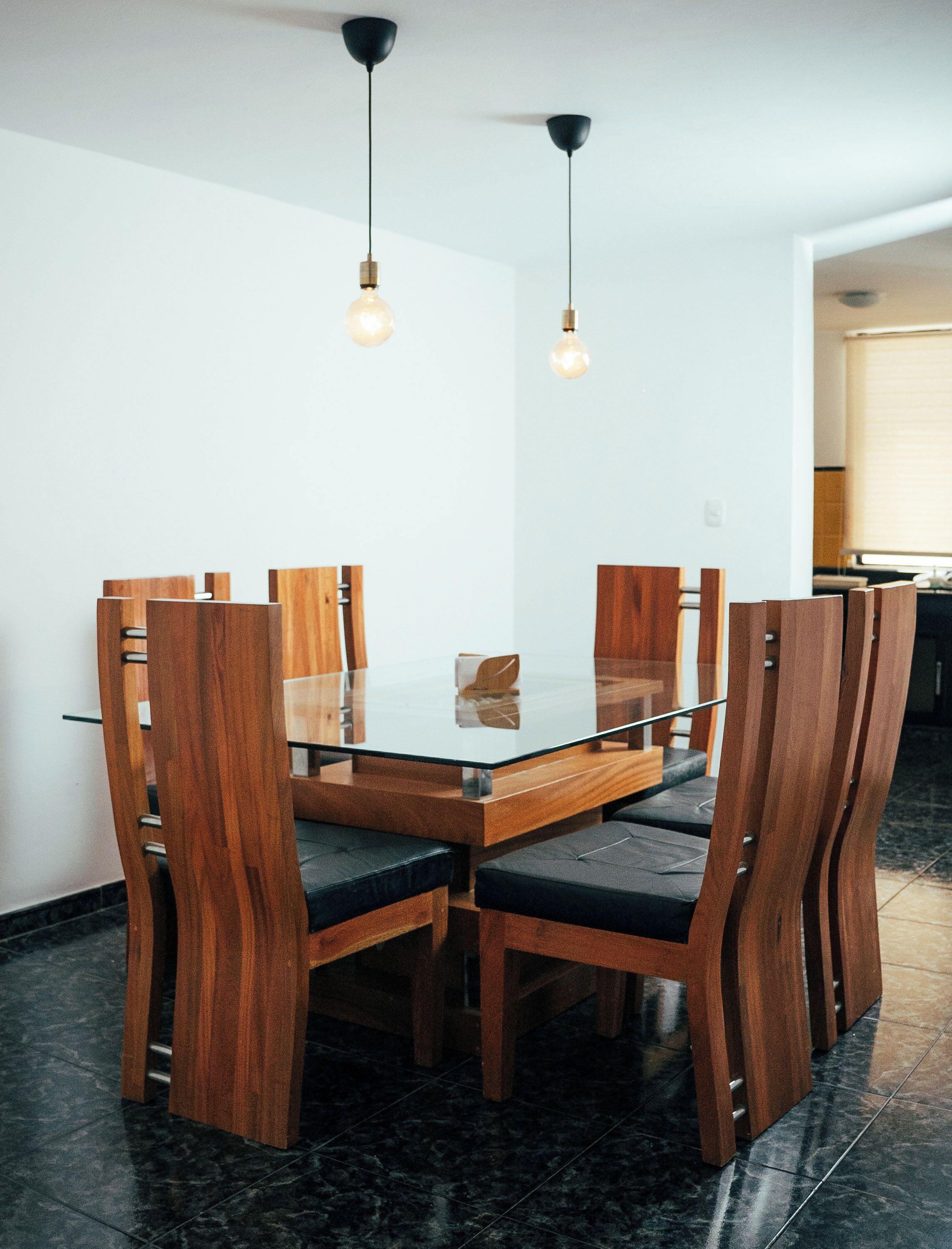 A modern dining area with a glass-top table surrounded by wooden chairs with cushioned seats.