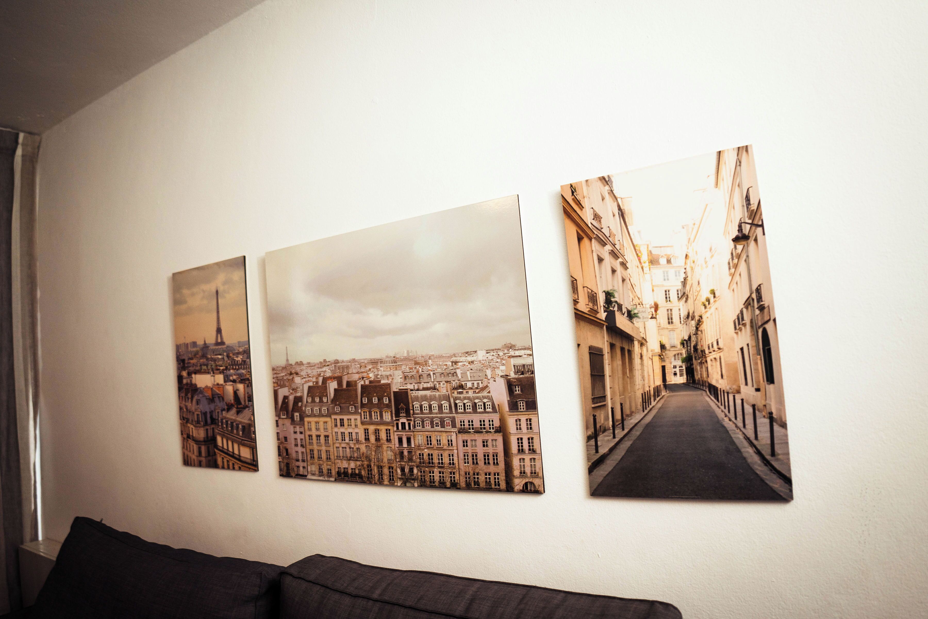Three framed cityscape photographs on a wall.
