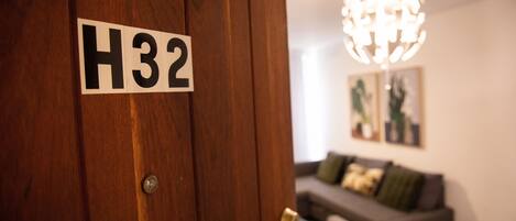 A wooden door with a sign reading "H32" and a modern chandelier in the background.