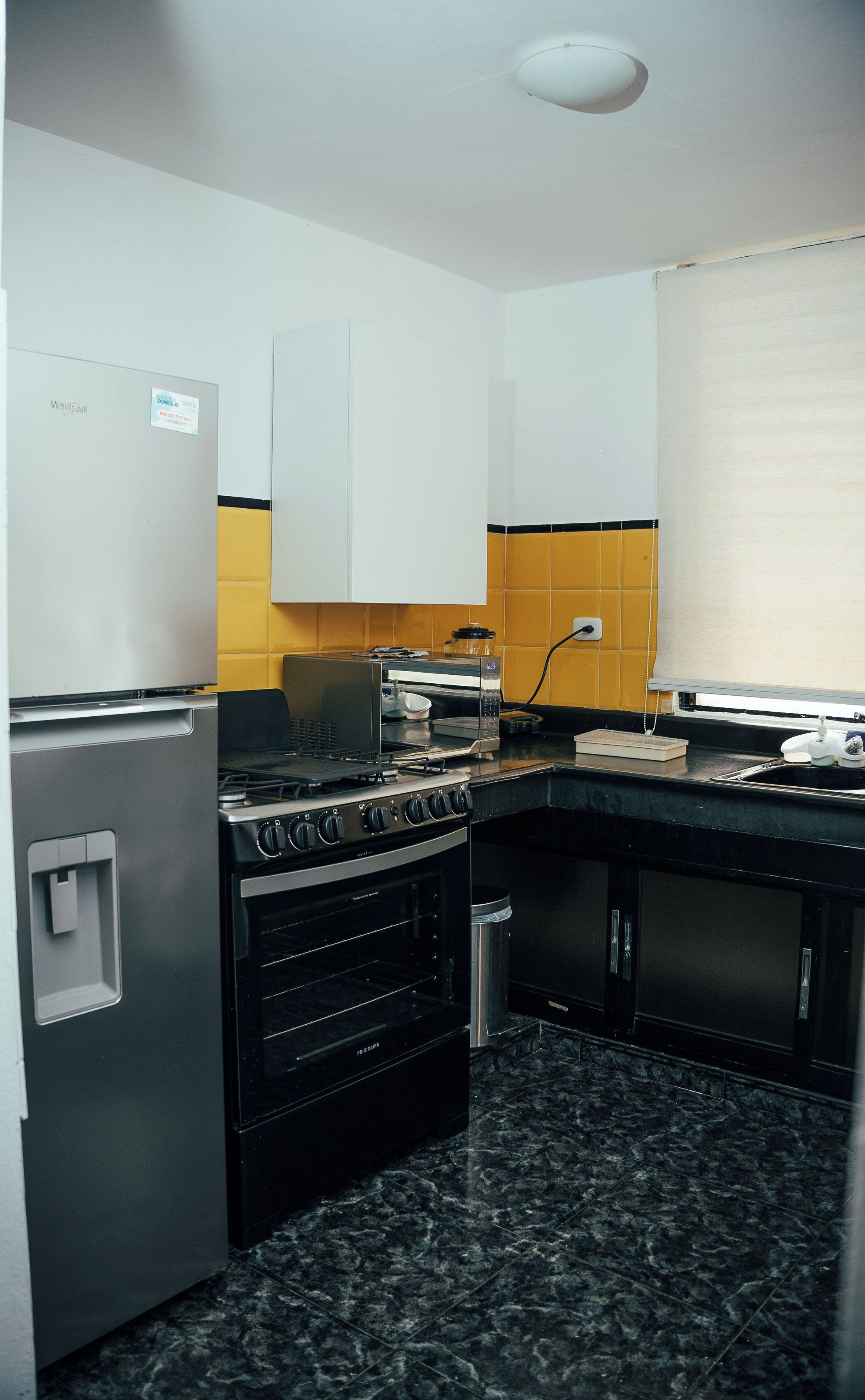 A compact kitchen with a refrigerator, stove, oven, and microwave.