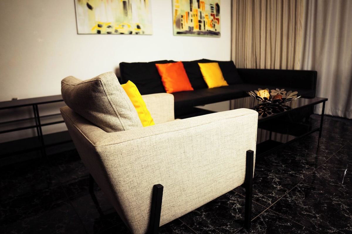 A modern living room with a sofa and armchairs, a coffee table, and artwork on the wall.