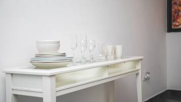 Una mesa blanca con platos apilados, vasos y un candelabro.