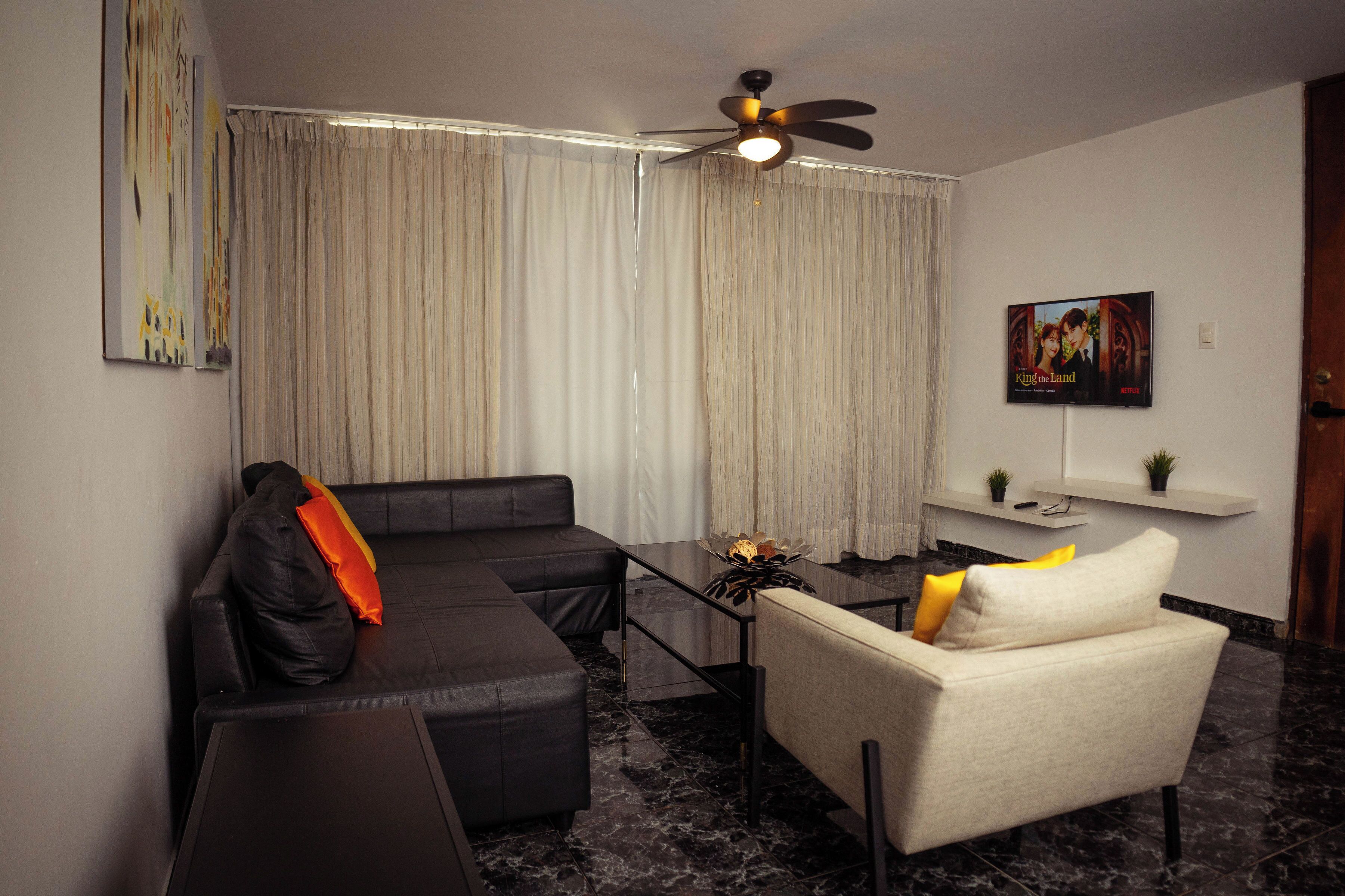 Een moderne woonkamer met een bank, fauteuil en een klein tafeltje met decoratieve objecten.