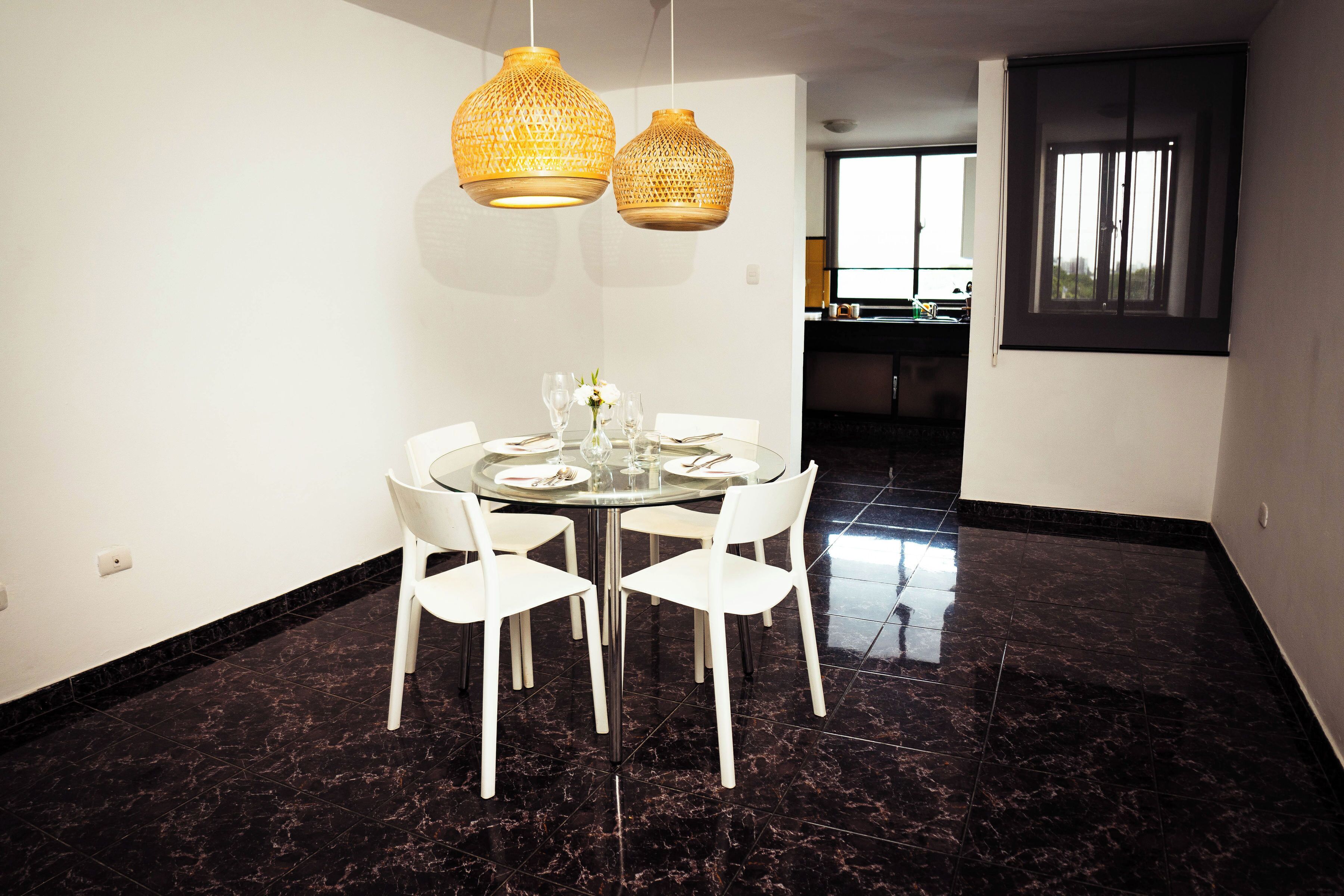 Un espace repas avec une table ronde, des chaises blanches et deux suspensions en fibres tressées.