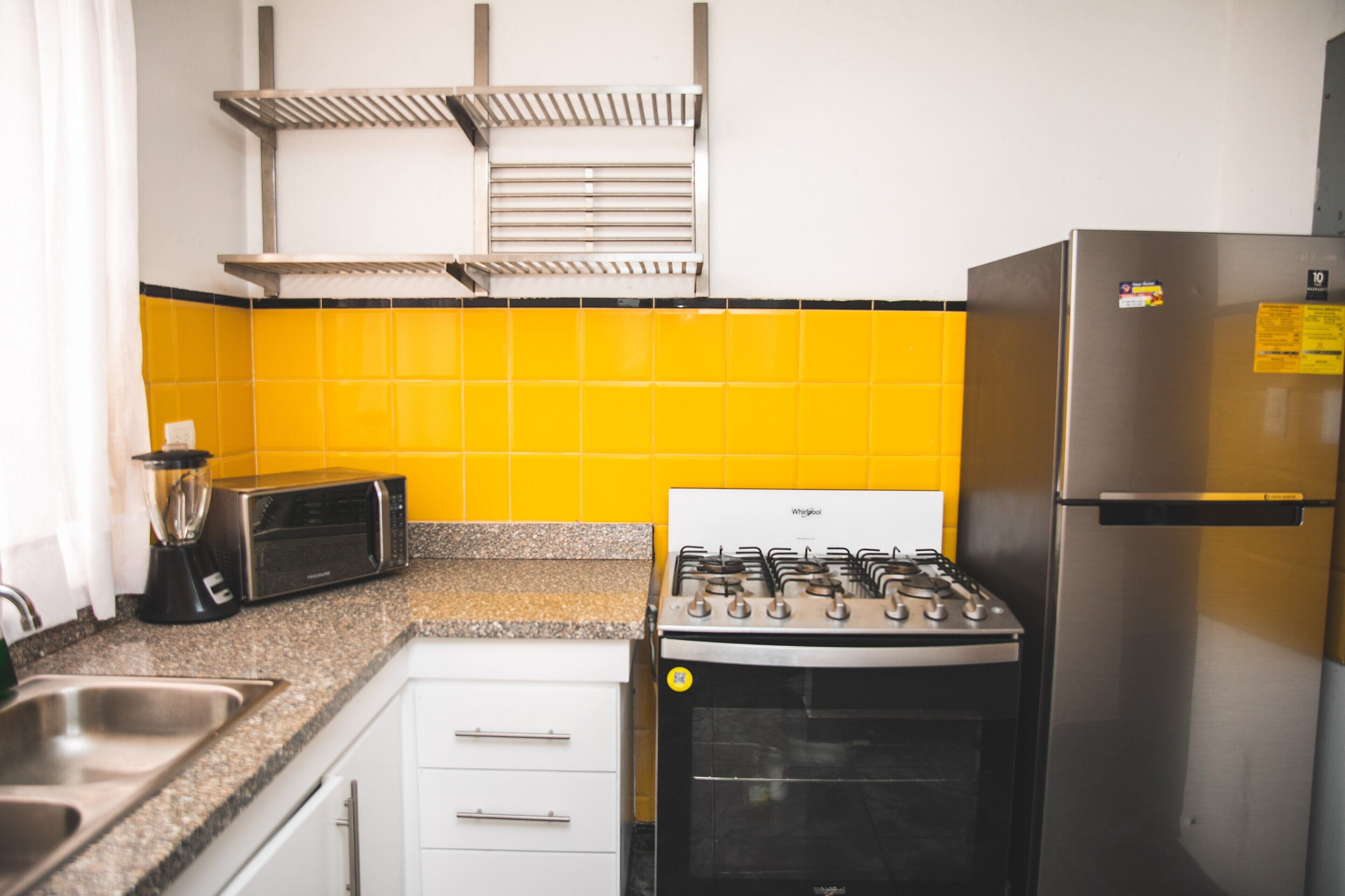 A kitchen with a gas stove, a refrigerator, a toaster, and a blender.