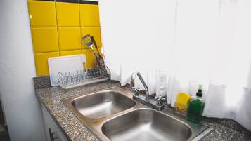 A kitchen with two stainless steel sinks, a dish rack, and a yellow backsplash.