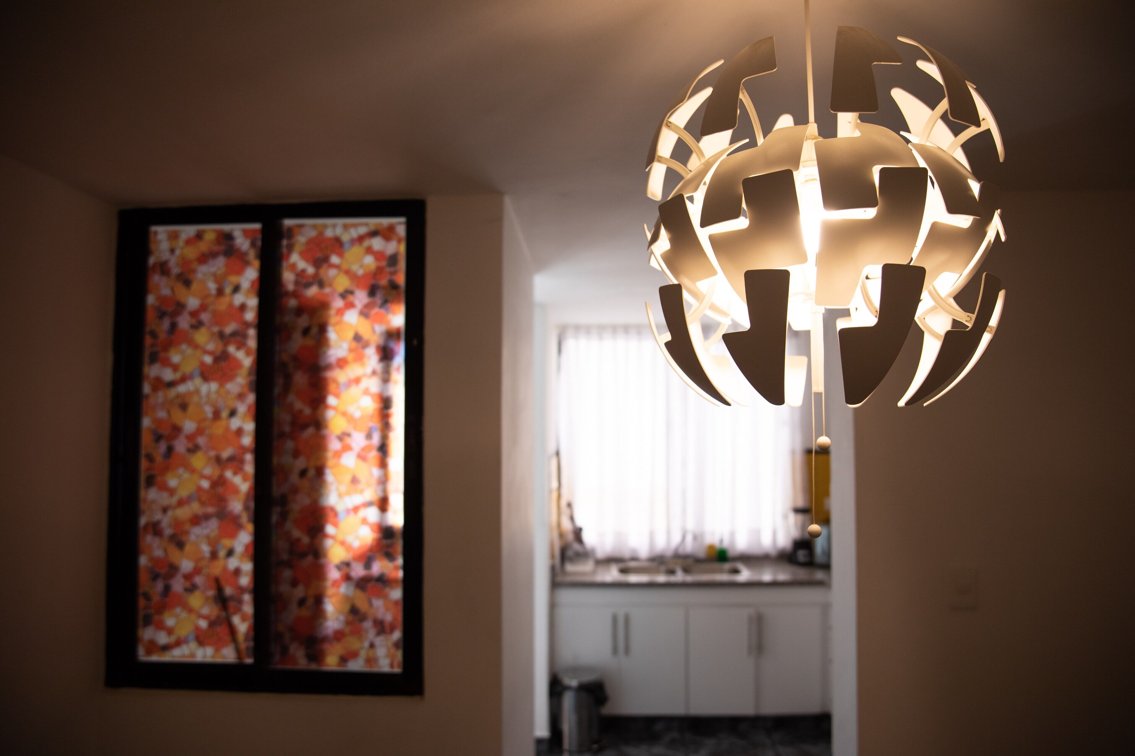 Um interior moderno com uma luminária esférica e uma pintura abstrata colorida na parede.
