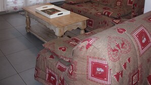 Ein Wohnzimmer mit einer Couch, einem Couchtisch und einer Tür mit gemusterten Vorhängen.