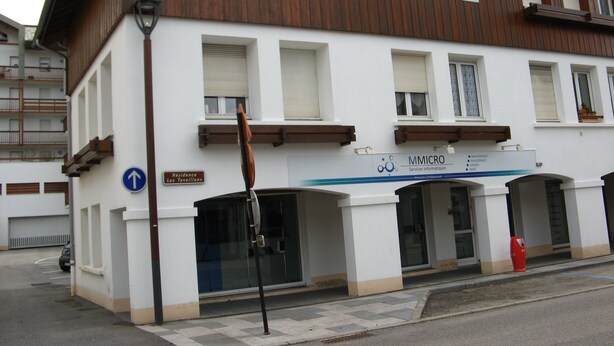 Ein Gebäude mit einem Schild, auf dem „MMICRO Services informatiques“ und ein Schild mit der Aufschrift „Résidence Les Tavaillons“ stehen.