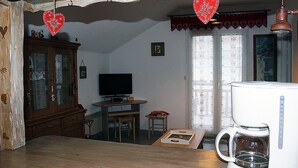 Ein gemütliches Wohnzimmer mit einem Holztisch, einem Fernseher, einem Schrank und einer Kaffeemaschine.
