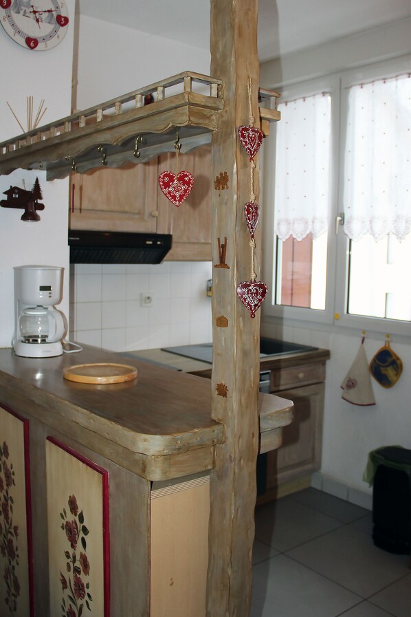 A kitchen with a wooden island, a coffee maker, and heart-shaped decorations. - Appartement AU Centre DU Village DES Rousses (Les Rousses)