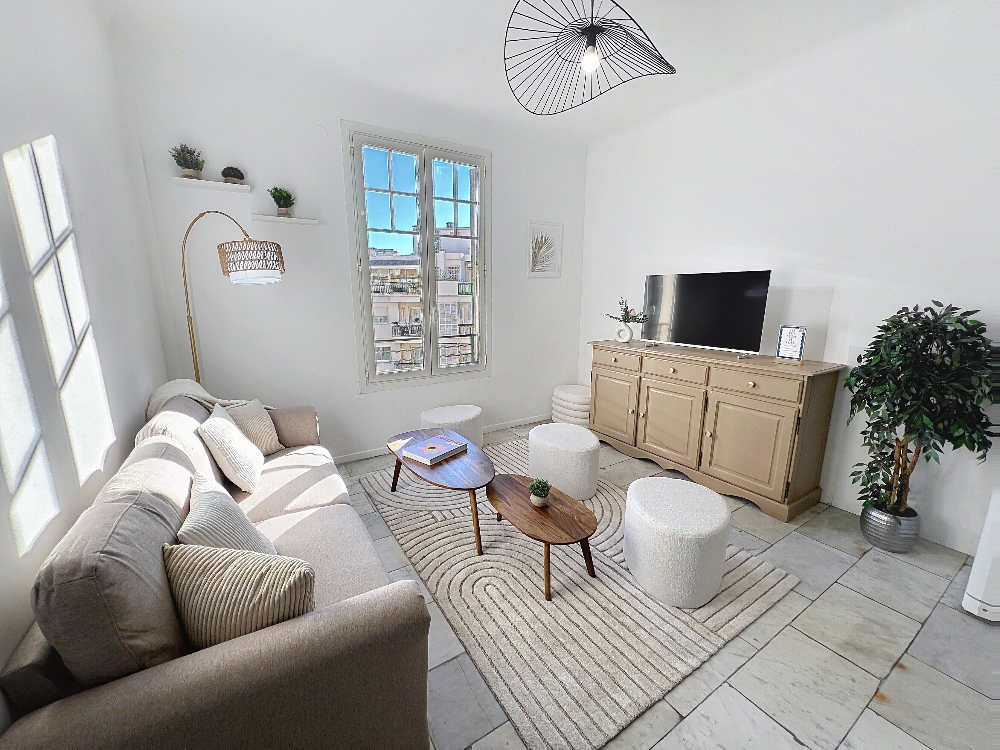 A modern living room with a sofa, coffee table, ottoman, and a TV on a wooden cabinet.