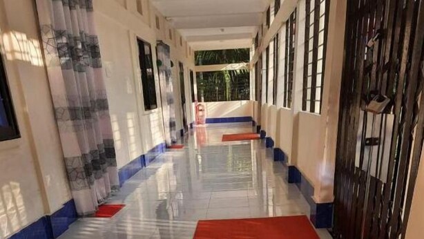 A corridor with a red carpet, tiled floor, and blue and white walls. - Sunapur Mini Resort (Bhurbhuria)