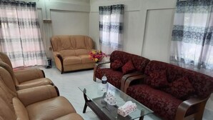 A living room with a beige sofa, a red sofa, and a glass coffee table. - Sunapur Mini Resort (Bhurbhuria)