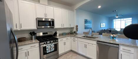 A modern kitchen with white cabinets, stainless steel appliances, and a granite countertop.