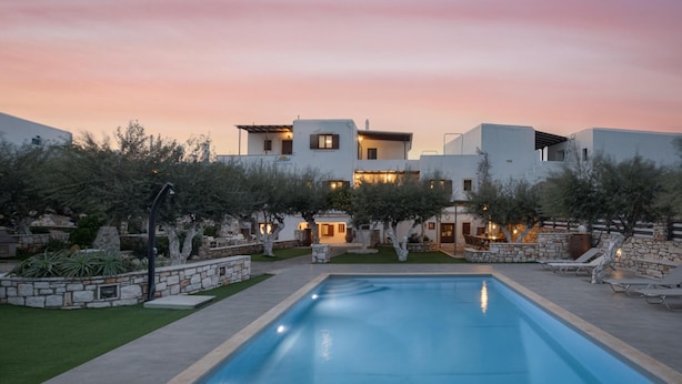 A modern villa with a swimming pool, stone walls, and outdoor seating areas. -  Sunset Paros Naousa (Paros)