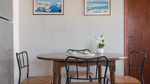 A dining table with four chairs, a vase with flowers, and two framed pictures on the wall. -  Sunset Paros Naousa (Paros)