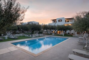Una piscina al aire libre, sombrillas, sillones reclinables de piscina