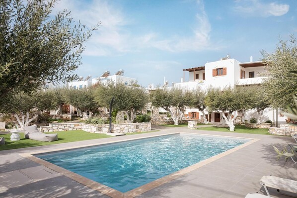 Una piscina al aire libre, sombrillas, sillones reclinables de piscina