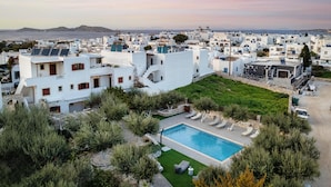 A residential area with white buildings, a swimming pool, and a view of the sea. -  Sunset Paros Naousa (Paros)