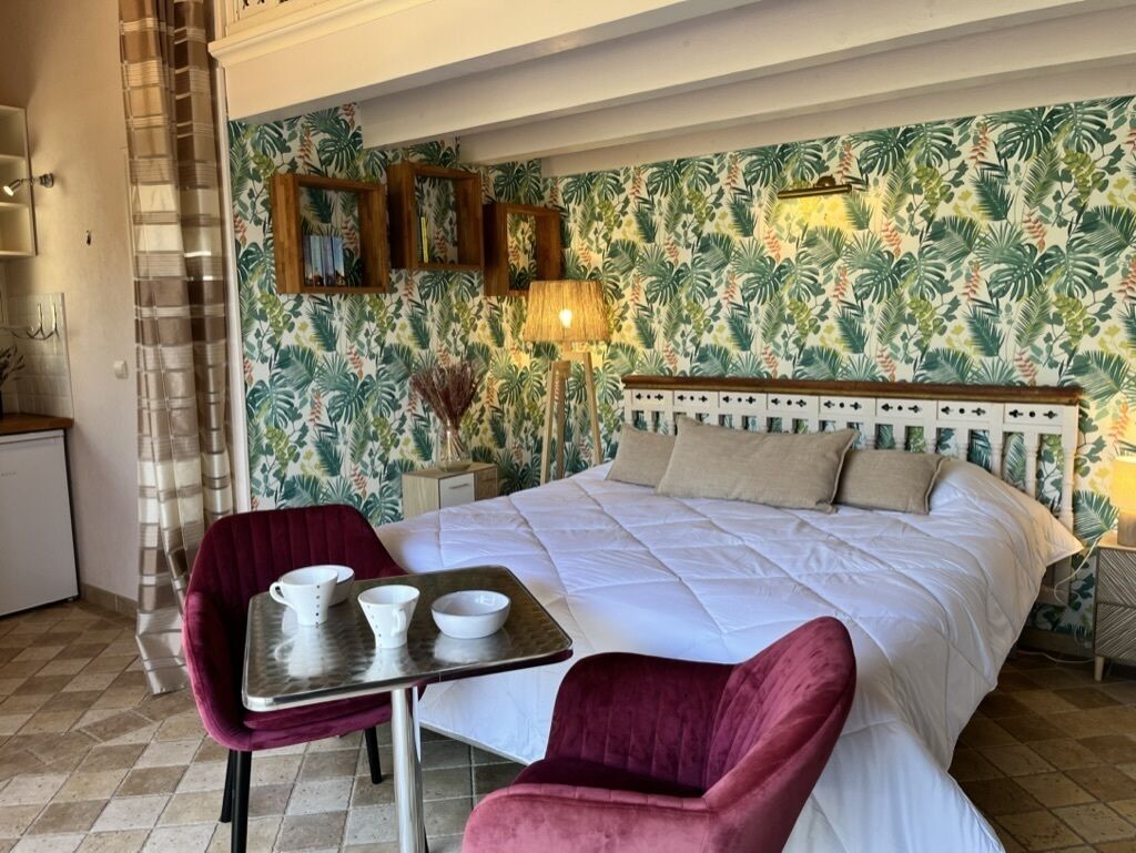 Une chambre avec un grand lit, une petite table avec des tasses et une chaise.