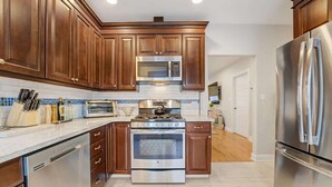 A modern kitchen with wooden cabinets, stainless steel appliances, and a tiled backsplash. - Beach Block Family House w/Garage & Decks (Sea Bright)