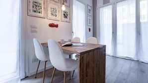 A dining area with a wooden table, white chairs, and framed botanical prints on the wall. - Italianway Comfort - Piranesi 18 B City Garden (Milan)