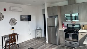 A modern kitchen with stainless steel appliances, a flat-screen TV, and decorative wall art. - Midtown’s Hidden Secret (Reno)